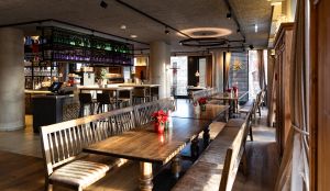 Rustikale Holztische und Bänke im hellen Gastraum mit roten Weihnachtssternen.