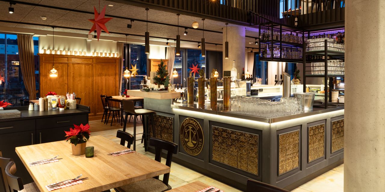 Gastraum mit Blick auf die Bar, eingedeckten Holztischen und roten Weihnachtssternen.