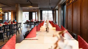 Perspektivische Ansicht einer langen, festlich eingedeckten Tafel mit roten Servietten.