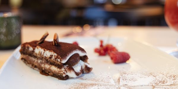 Ein Stück Tiramisu mit Kakaopulver, garniert mit frischen roten Johannisbeeren.