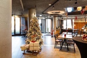 Festlich geschmückter Weihnachtsbaum auf einem Schlitten im sonnendurchfluteten Gastraum.