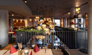 Blick über eine Galerie mit Tannengirlande auf hängende Designerleuchten im Atrium.