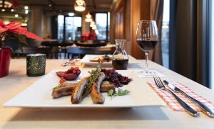 Gebratene Würstchen mit Rotkohl und garniertem Apfel auf einem weißen Teller.