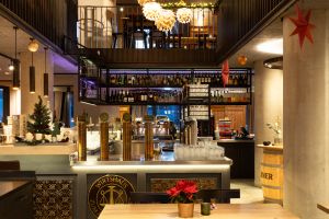 Zentrale Bar mit Zapfanlagen, Gläserregalen und weihnachtlicher Girlande.