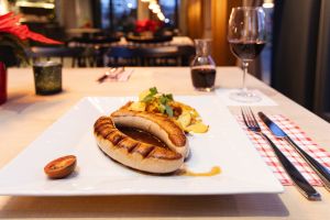 Große Bratwurst in dunkler Soße mit Röstkartoffeln und Petersilie.